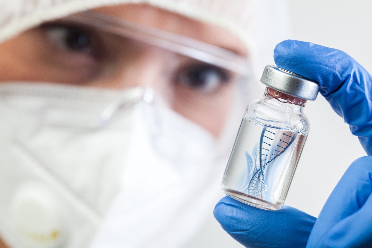 Female NHS UK lab microbiologist biotechnician holding glass bottle vial with DNA helix strand float in liquid,Coronavirus new strain mutation,novel Omicron variant,COVID-19 pandemic crisis outbreak; Shutterstock ID 1881780373; purchase_order: IWD; job: ; client: ; other: 