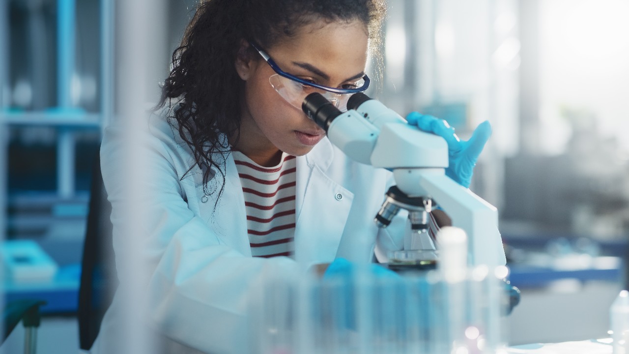 Medical Science Laboratory: Portrait of Beautiful Black Scientist Looking Under Microscope Does Analysis of Test Sample. Ambitious Young Biotechnology Specialist, working with Advanced Equipment; Shutterstock ID 1922200124; purchase_order: Life Sciences (LS); job: Website Design; client: Brianna Backes (Martech); other: For Andrea Tomovici (LS)